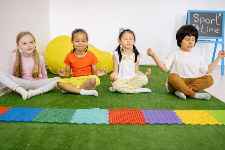 Kinder sitzen in Yogahaltung auf einer Matte